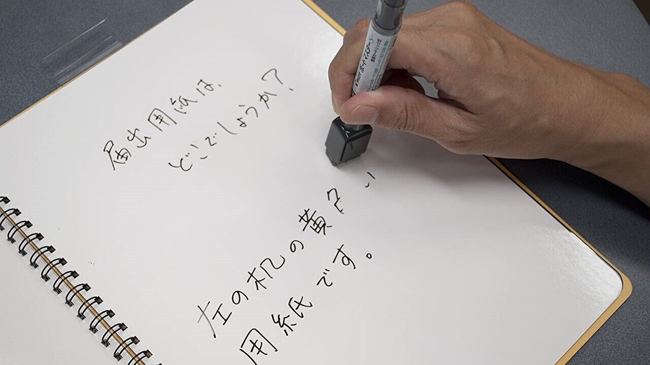A hand writing on a spiral notebook with a pen.