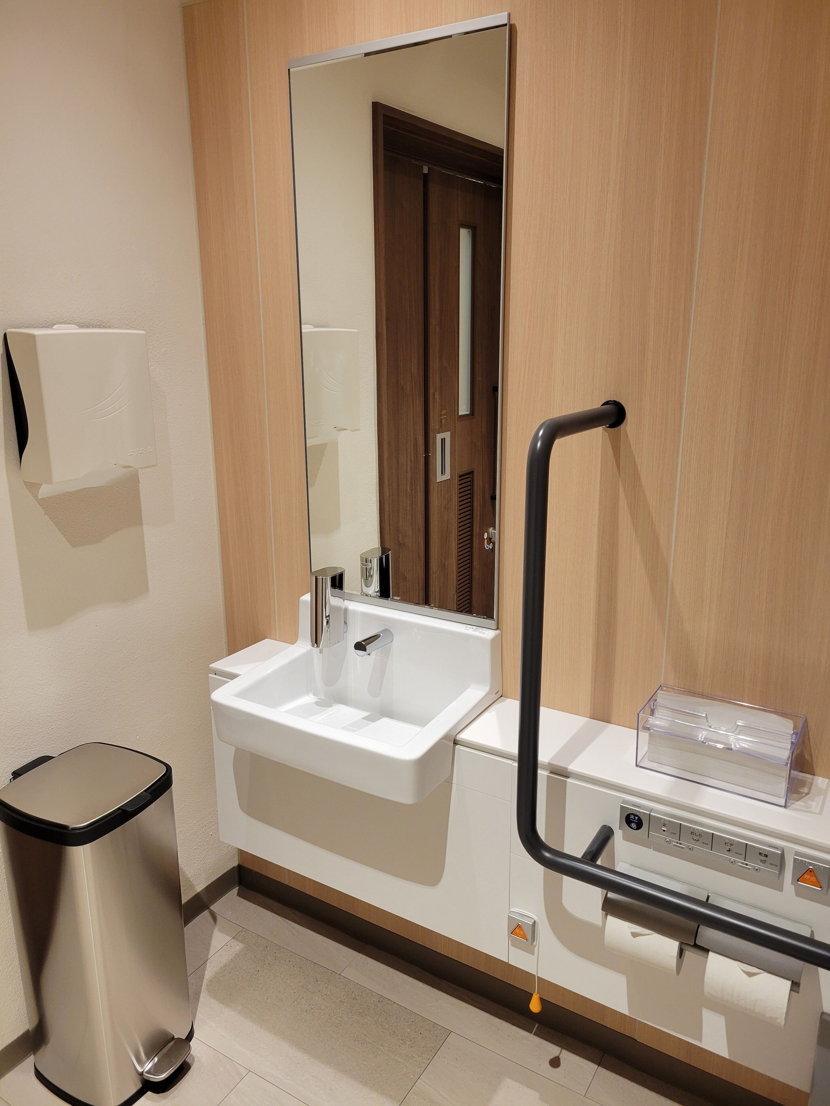 A modern bathroom with a sink, mirror, and hand dryer.