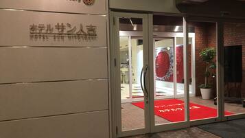 A hotel entrance with a sign reading "Rotary Hotel" and a red carpet with Japanese characters.
