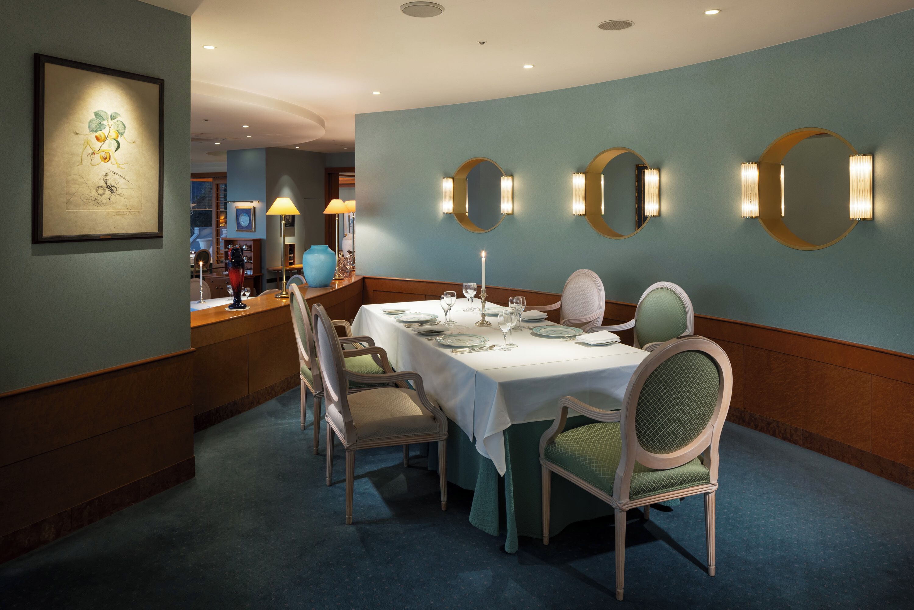 A dining area with a table set for four, surrounded by chairs with cushioned seats.