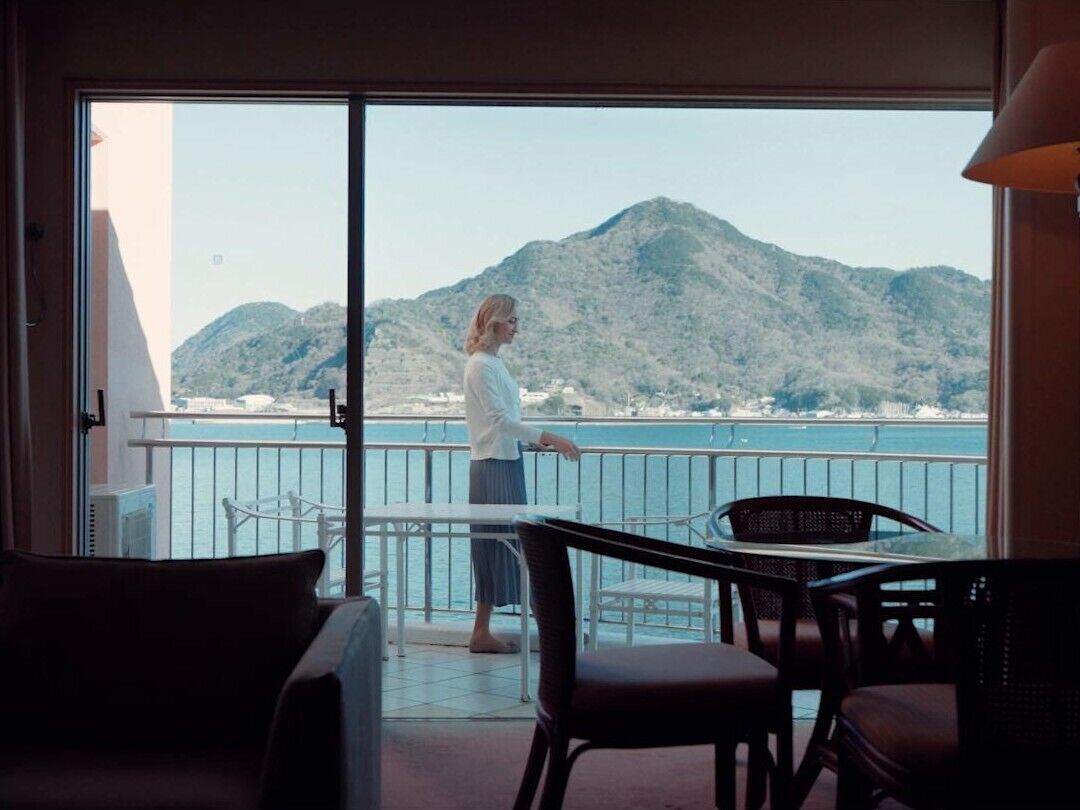 Un balcón con vista al mar y a las montañas, una mesa y dos sillas.