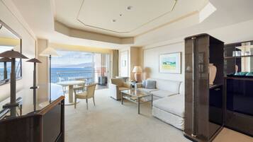 A hotel room with a balcony, a sofa, a coffee table, and a TV.