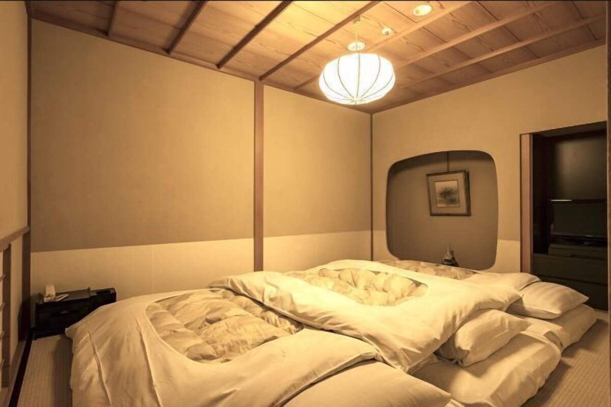 Un dormitorio con cama, mesita de noche, lámpara de pared y una puerta.