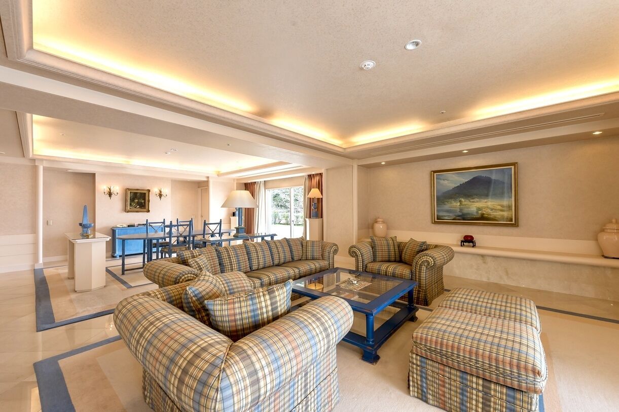 A spacious living area with a sofa set, a coffee table, and a dining area with chairs and a table.