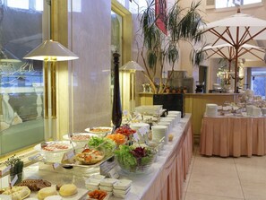 A buffet setup with various food items and a large window in the background.
