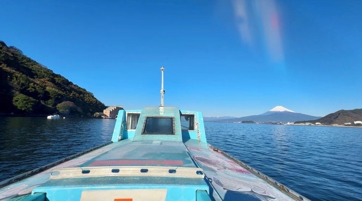 A boat with a cabin and a view of a mountain in the distance.