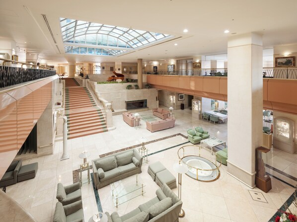 Un vestíbulo amplio con una zona de estar central, una escalera y un techo de cristal.