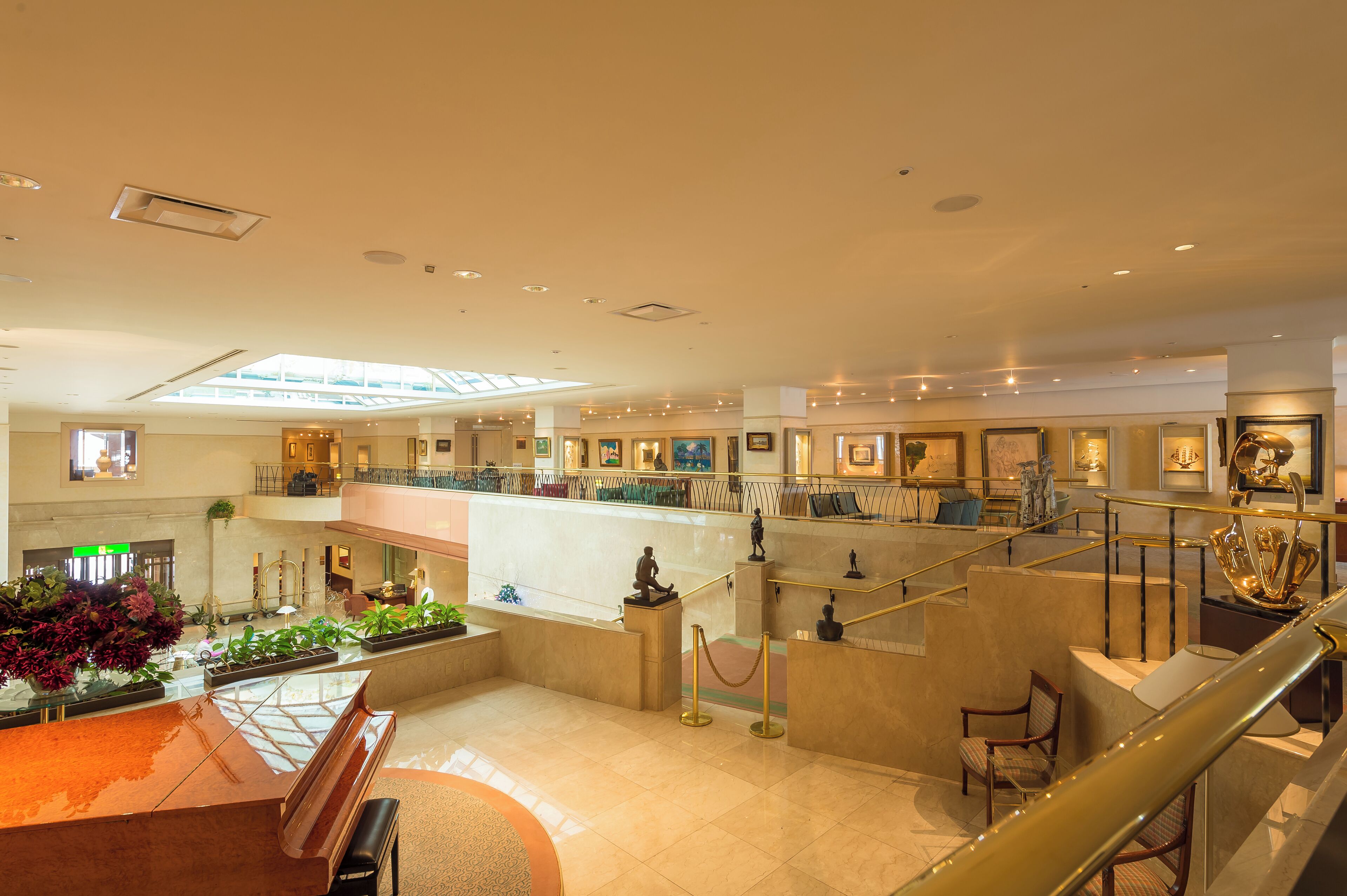 A spacious lobby with a central seating area, a staircase, and a glass ceiling.