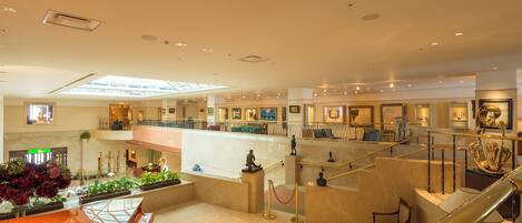 A spacious lobby with a central seating area, a staircase, and a glass ceiling.