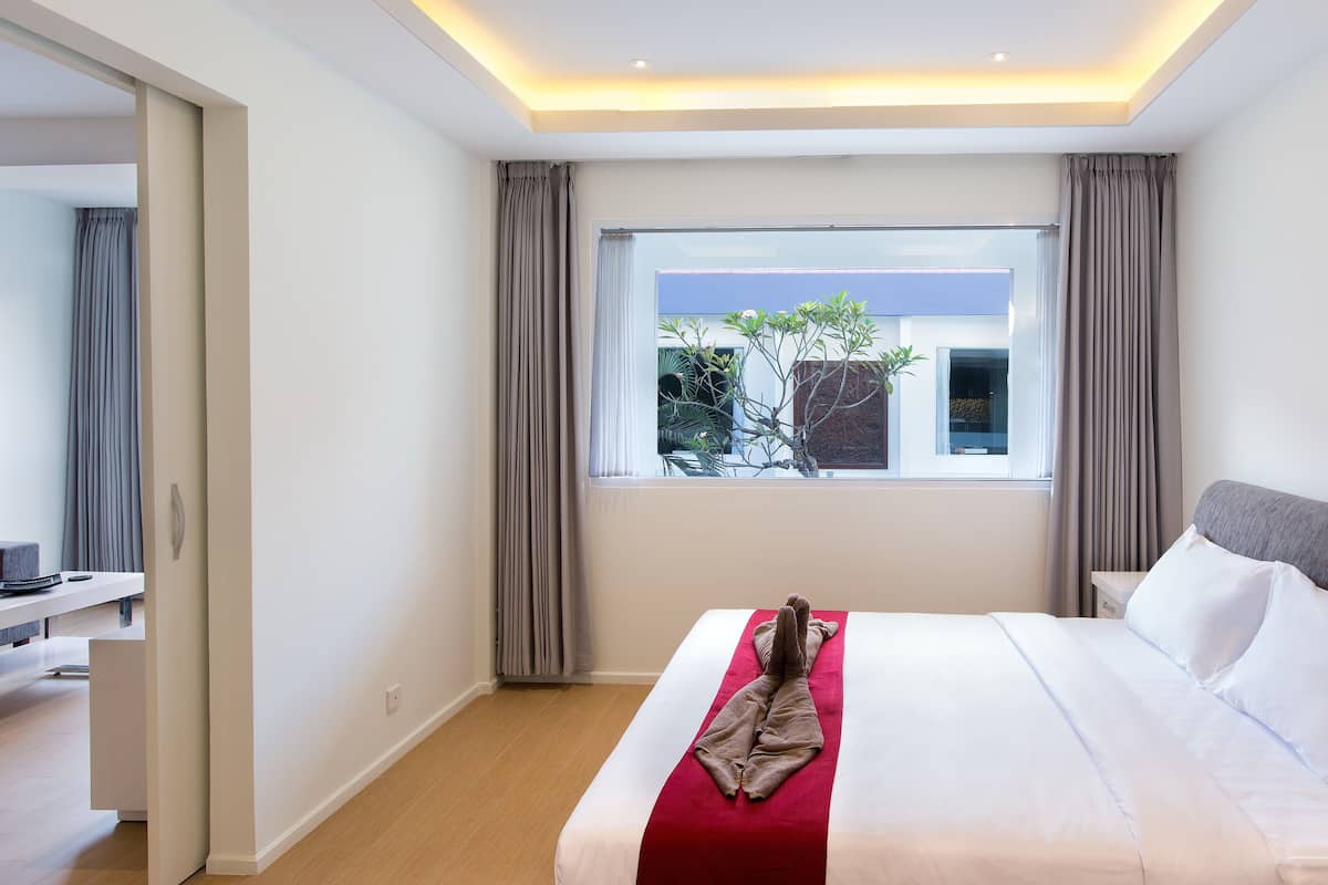 Une chambre d’hôtel avec un lit, un bureau et une fenêtre avec des rideaux.