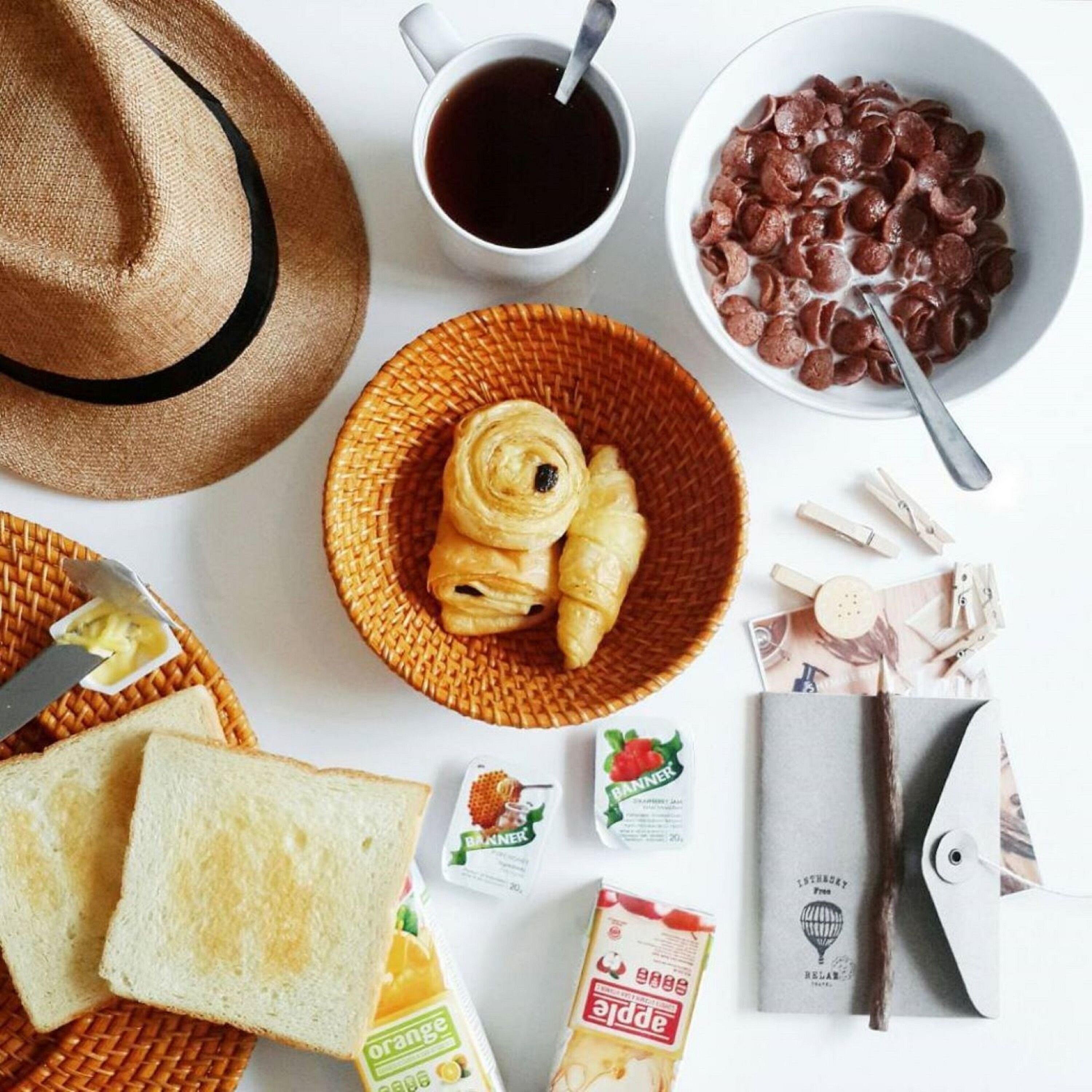 A breakfast setting with bread, croissants, a cup of coffee, chocolate cookies, and various breakfast items.
