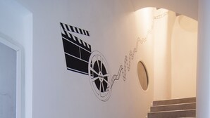 A staircase with a handrail, a wall-mounted light fixture, and a clapperboard and film reel decoration. - B&B Torino Très Chic (Turin)