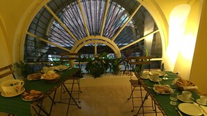 A dining area with a large arched window, green tablecloths, and a variety of dishes and drinks. - B&B Torino Très Chic (Turin)