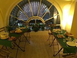 Zona pranzo con un'ampia finestra ad arco, tovaglioli verdi e una varietà di piatti e bevande.