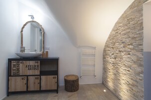 Un bagno con un mobile vanitario in legno, uno specchio e una parete in pietra.