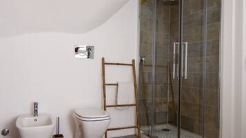 A bathroom with a glass shower enclosure, a white sink, and a toilet.