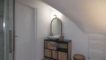 A bathroom with a white vanity, a large mirror, and a radiator.