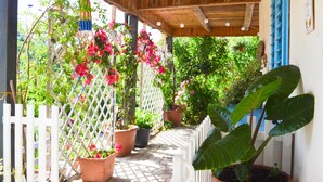 Un espace extérieur abrité, doté d’un plafond en bois, d’une clôture en treillis blanc et de plantes en pot.