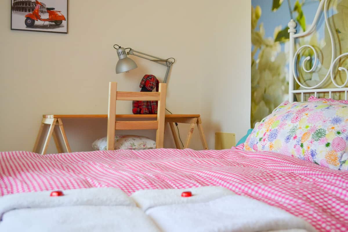 Una camera da letto con un letto, una scrivania, una lampada e una sedia.