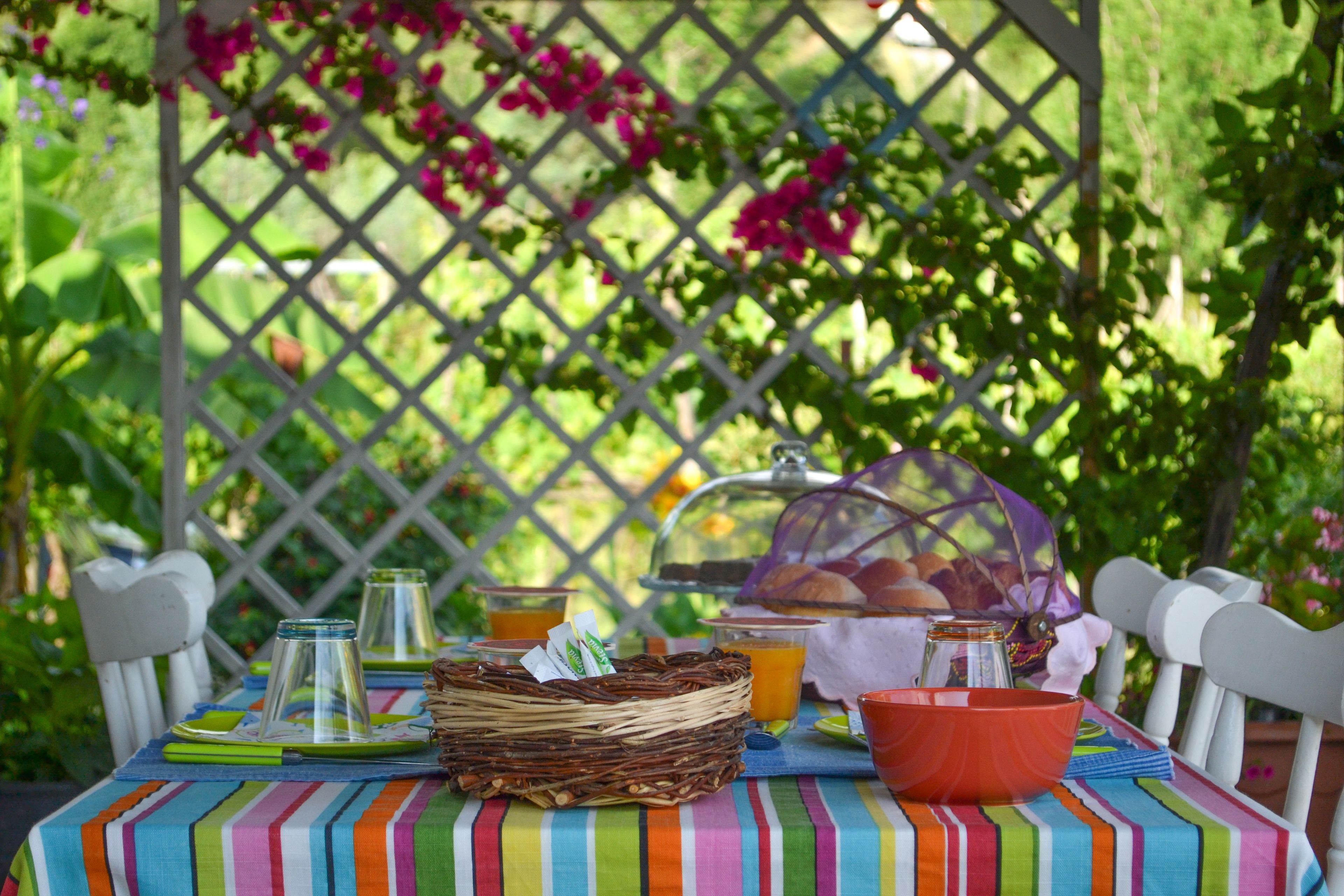 Une table dressée pour le petit-déjeuner, avec un panier en osier, des verres, un bol et un panier de pain.
