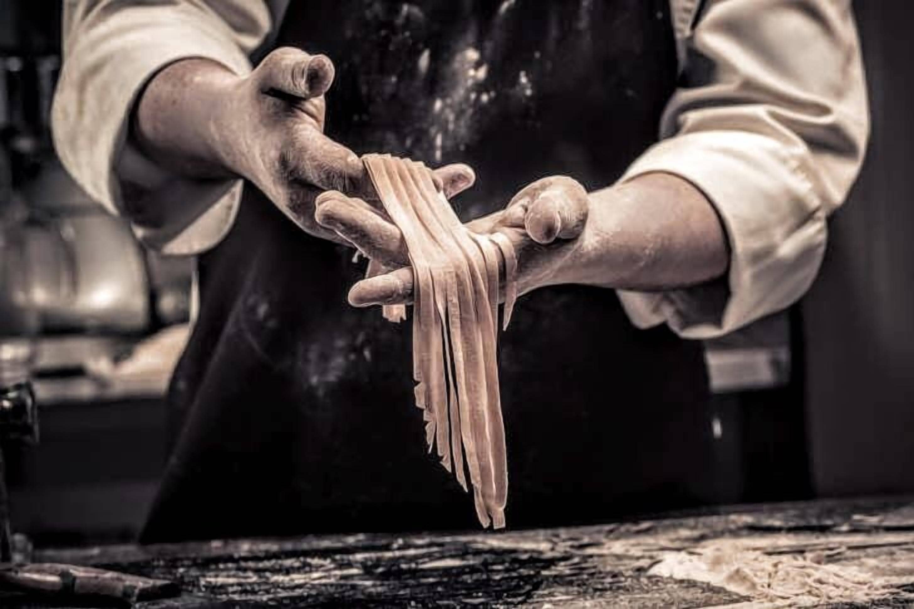A person handling pasta in a kitchen setting.
