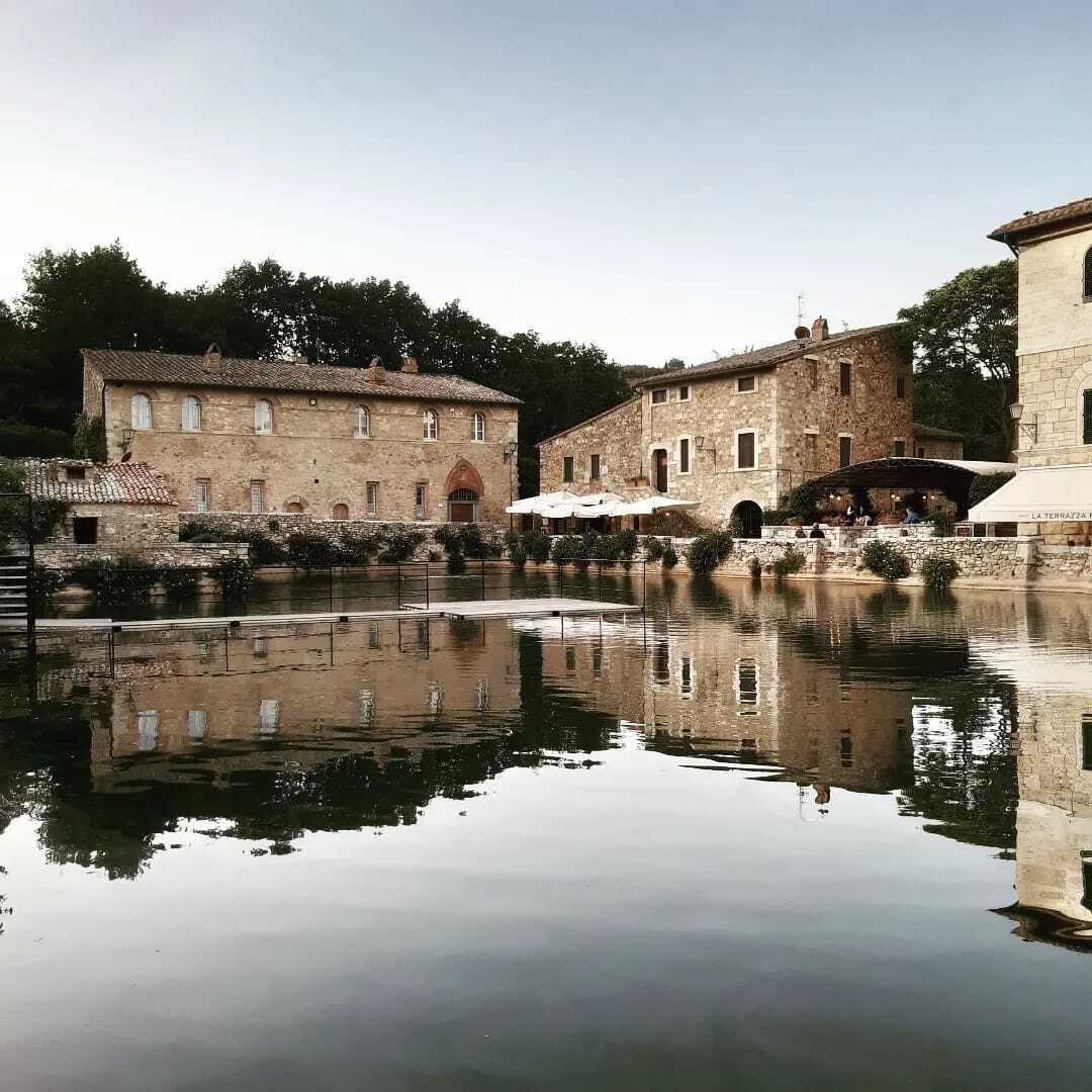 Ein historisches Steinhaus mit Innenhof und einer kleinen Brücke über einem stillen Wasserspiegel.