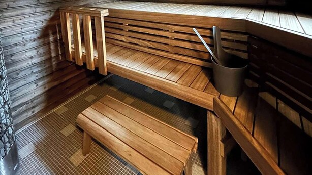 Una sauna con bancos de madera y un cubo de metal.