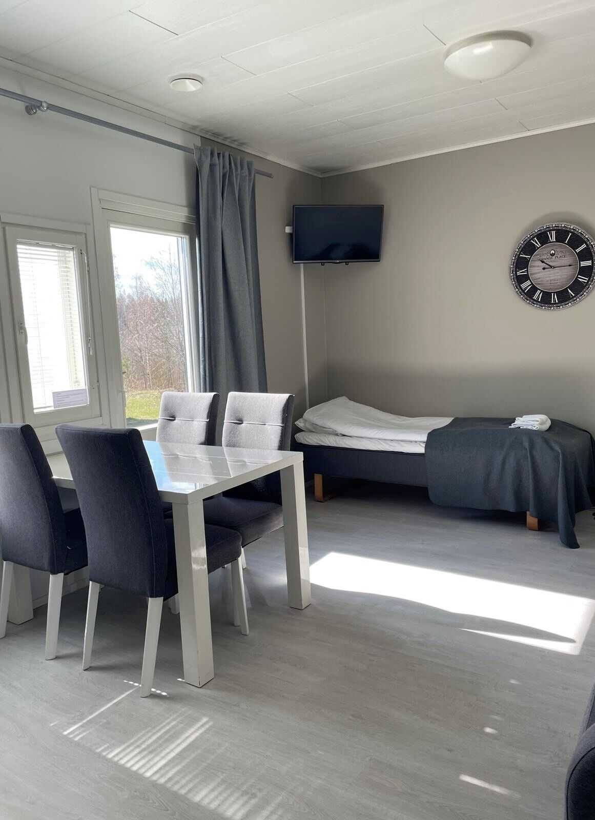 Une chambre moderne équipée d’une table à manger, de chaises, d’un lit et d’un téléviseur fixé au mur.