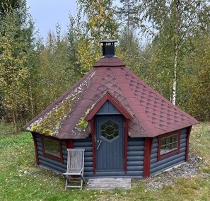 A log cabin with a triangular roof, a chimney, and a small porch. - Hotel Kontio (Kontiolahti)