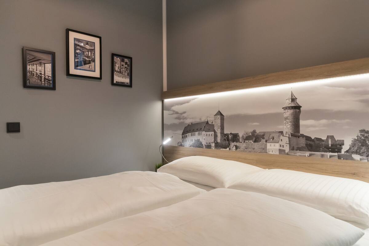 Un dormitorio con una cama grande, un cabecero con un mural de la ciudad y tres cuadros en la pared.