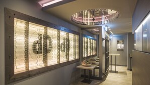 A hallway with a glass display case filled with cylindrical objects, a wooden floor, and a ceiling light fixture. - dasPaul Hotel (Nuremberg)
