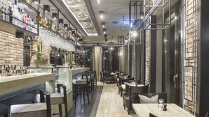 A bar area with a long counter, multiple seating options, and a staircase leading to an upper level. - dasPaul Hotel (Nuremberg)