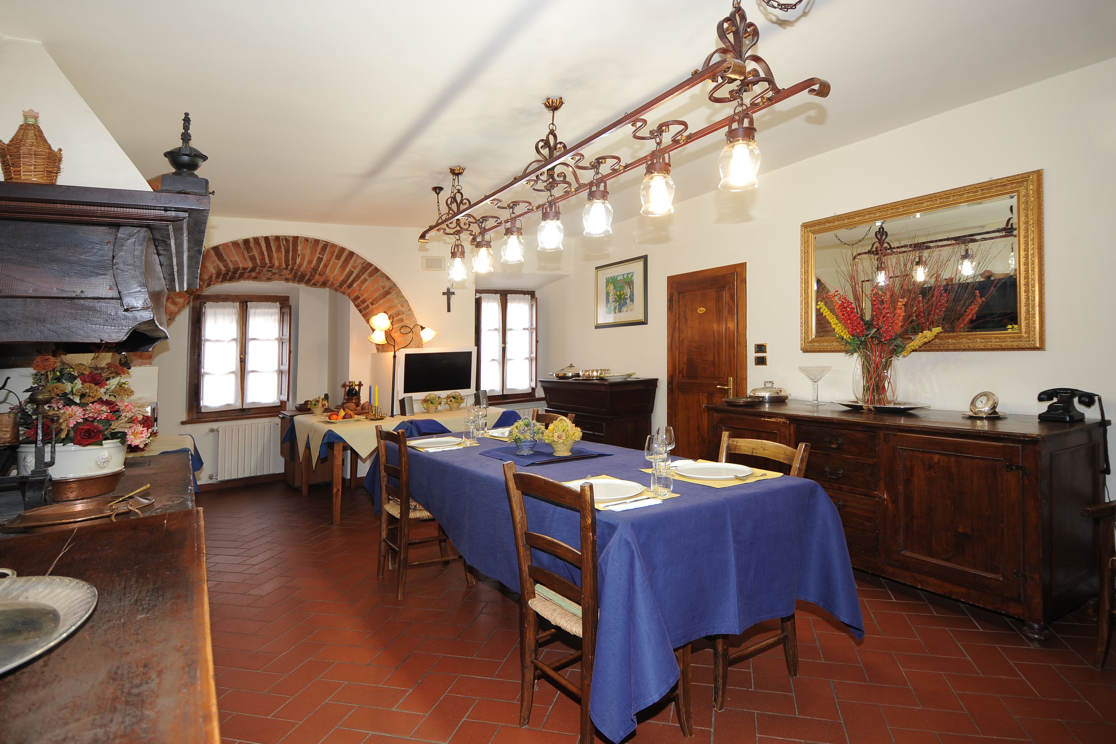 A dining room with a long table set for a meal, a wooden cabinet, and a mirror on the wall.