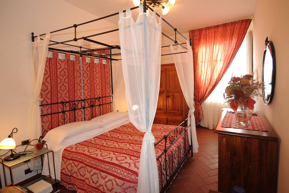 Ein Schlafzimmer mit einem Himmelbett, einem Nachttisch mit Lampe und einem Holzschrank.