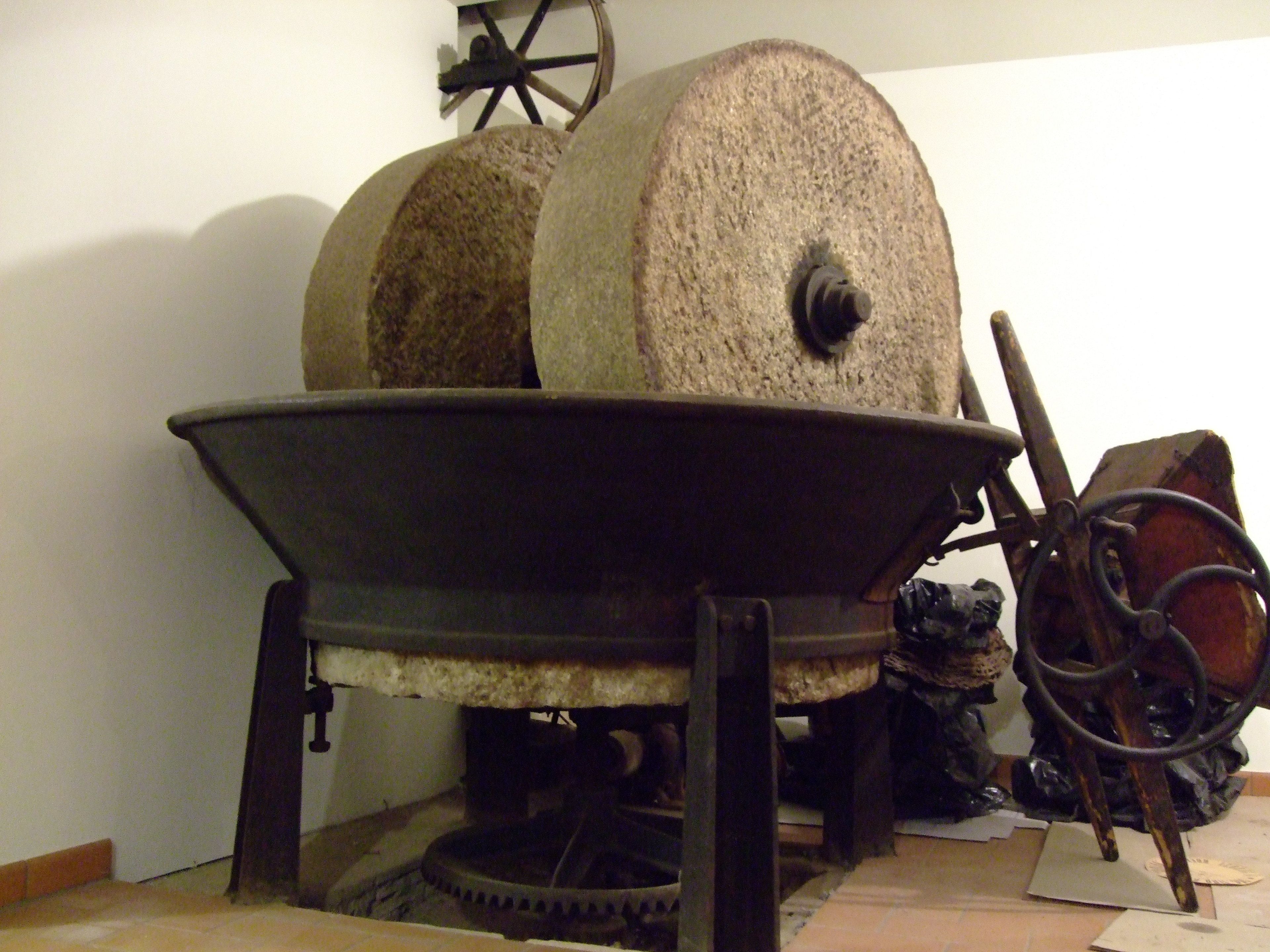 A large stone mill with a wooden wheel and a metal basin.