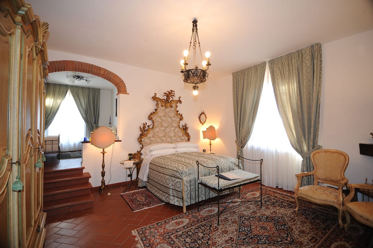 Ein Schlafzimmer mit einem Bett, einem Sessel, einer Deckenleuchte und einer Treppe.
