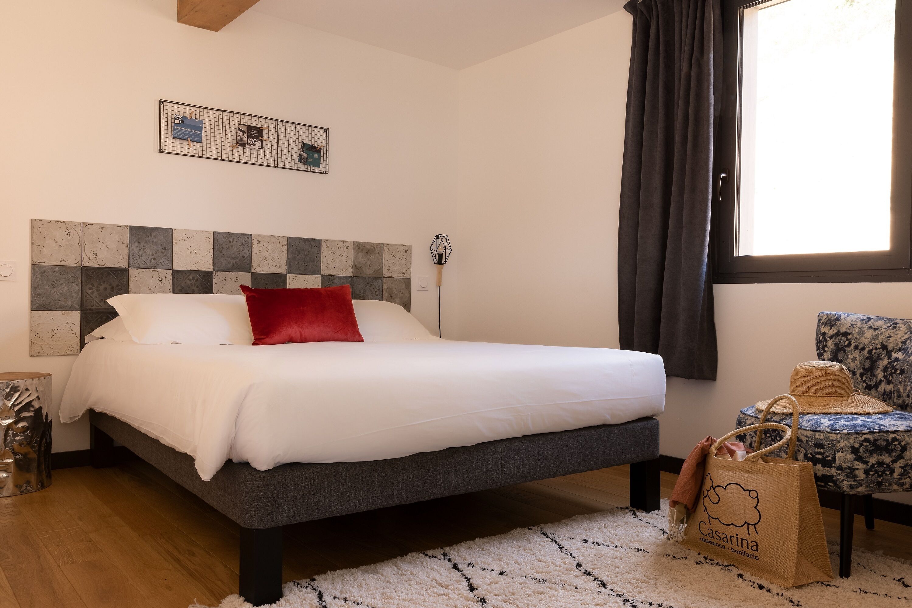 Une chambre à coucher comprenant un lit, une chaise, une fenêtre et un luminaire fixé au mur.