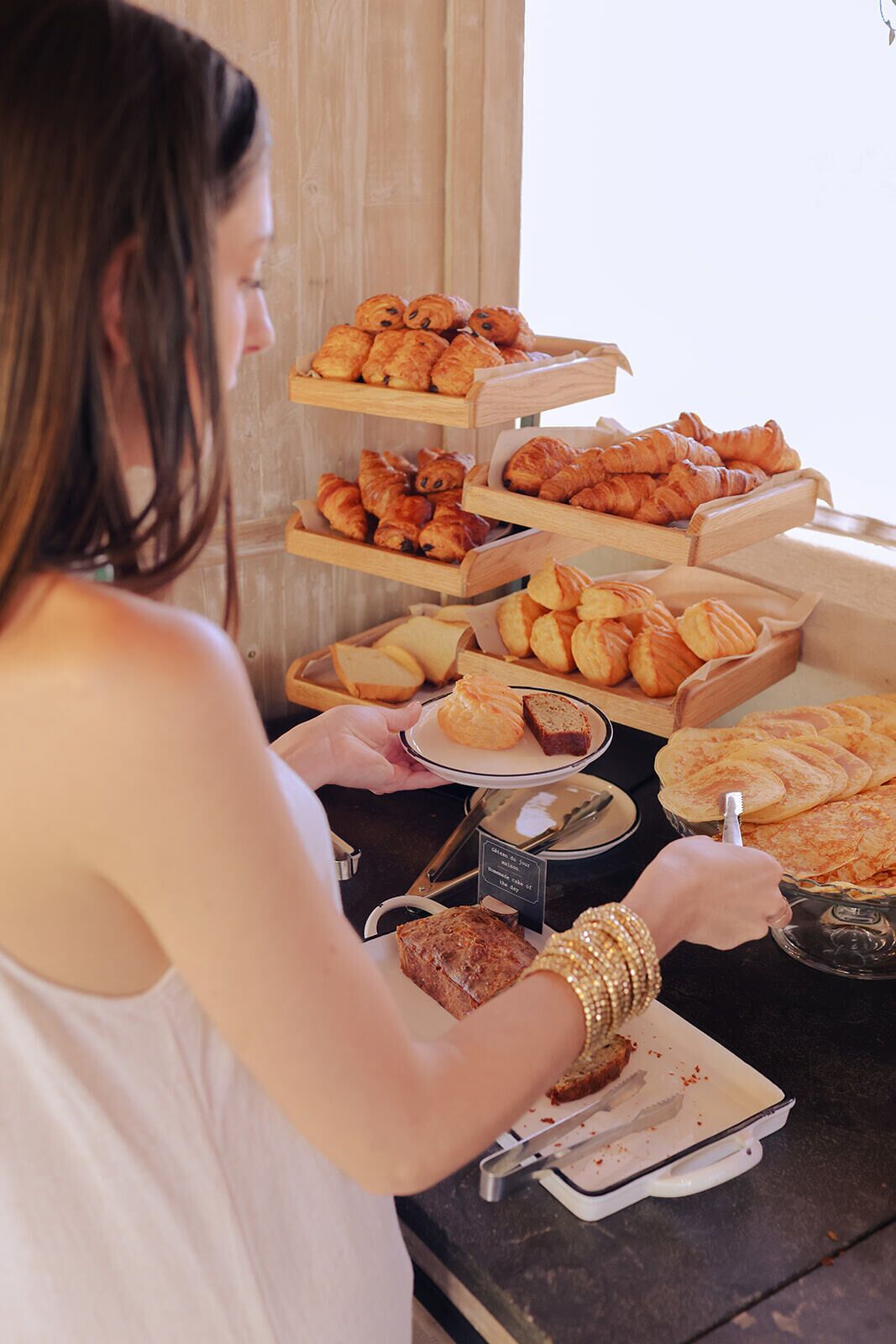 A buffet with various baked goods and a person serving themselves.