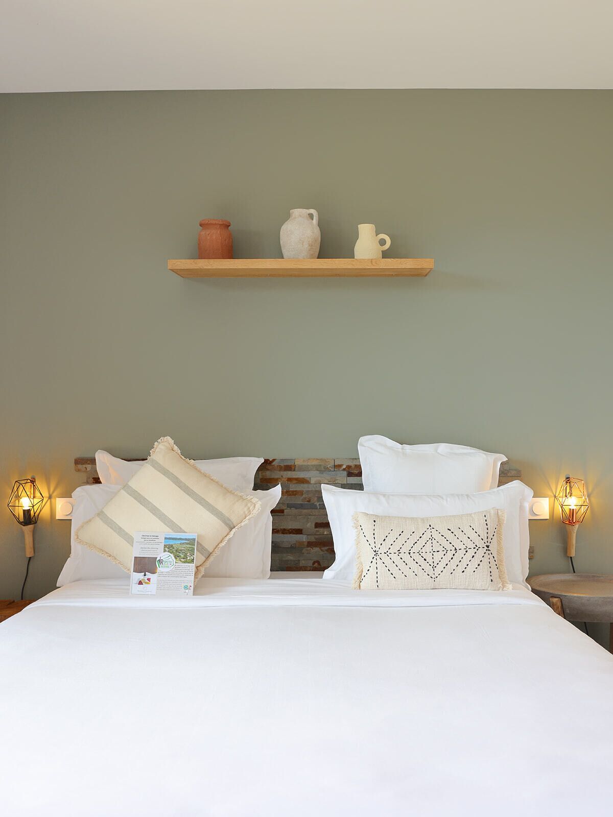 A bed with white bedding, a wooden headboard, and decorative pillows.