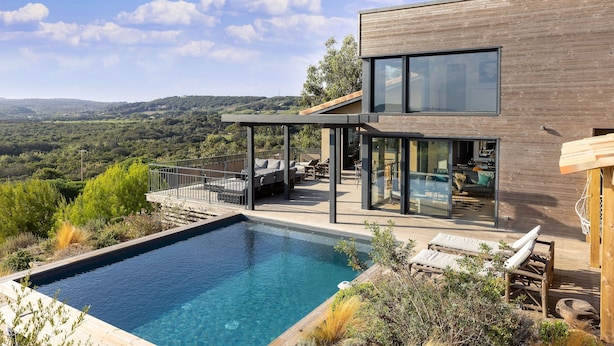A modern house with a swimming pool, outdoor seating, and a view of the countryside. - Résidence Casarina (Bonifacio)