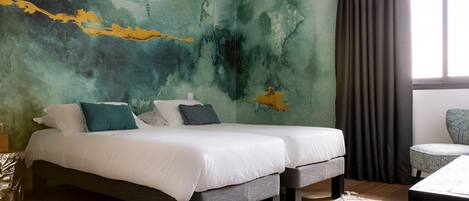 A modern bedroom with two beds, a large abstract mural, and a view of the outdoors through a window with curtains.