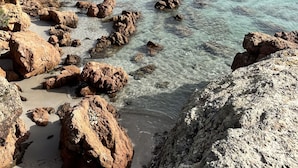 A rocky beach with clear turquoise water, boats, and distant hills. - Résidence Casarina (Bonifacio)