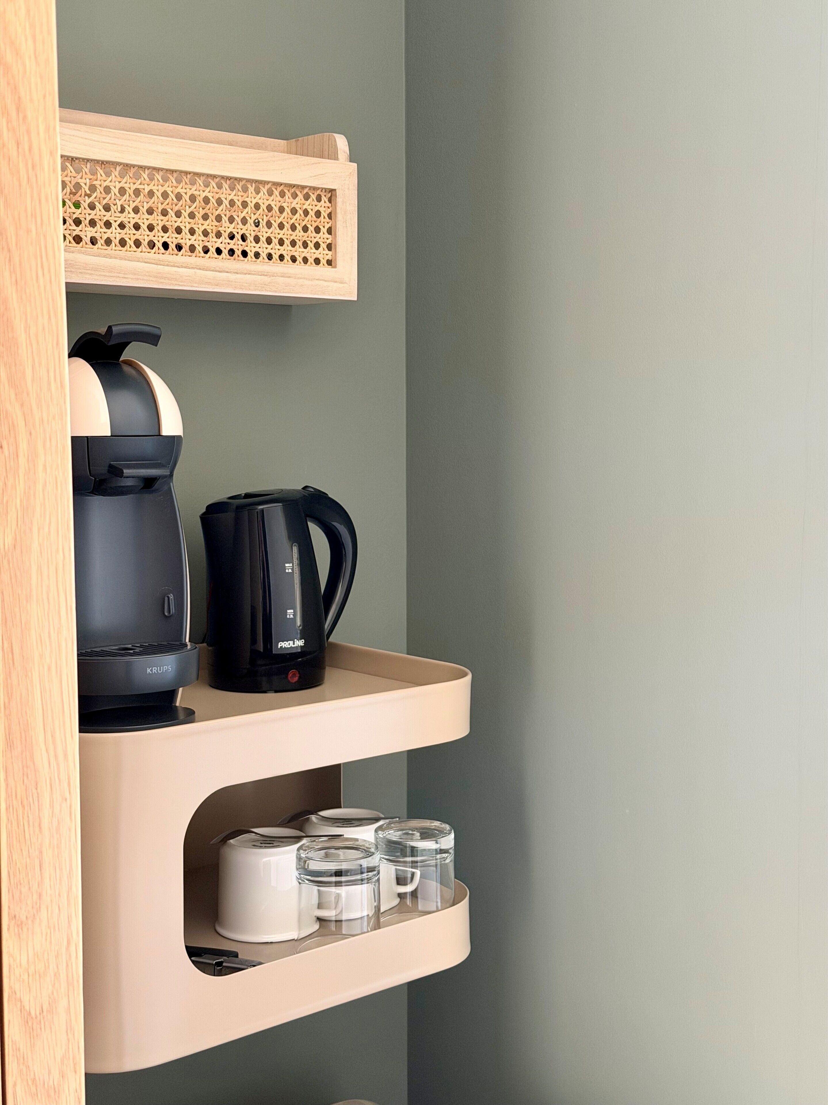 A kitchenette with a coffee maker, kettle, and storage containers.