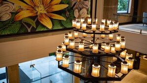 Un lustre à plusieurs lampes dans un hall d’entrée, avec une grande fresque florale sur le mur.