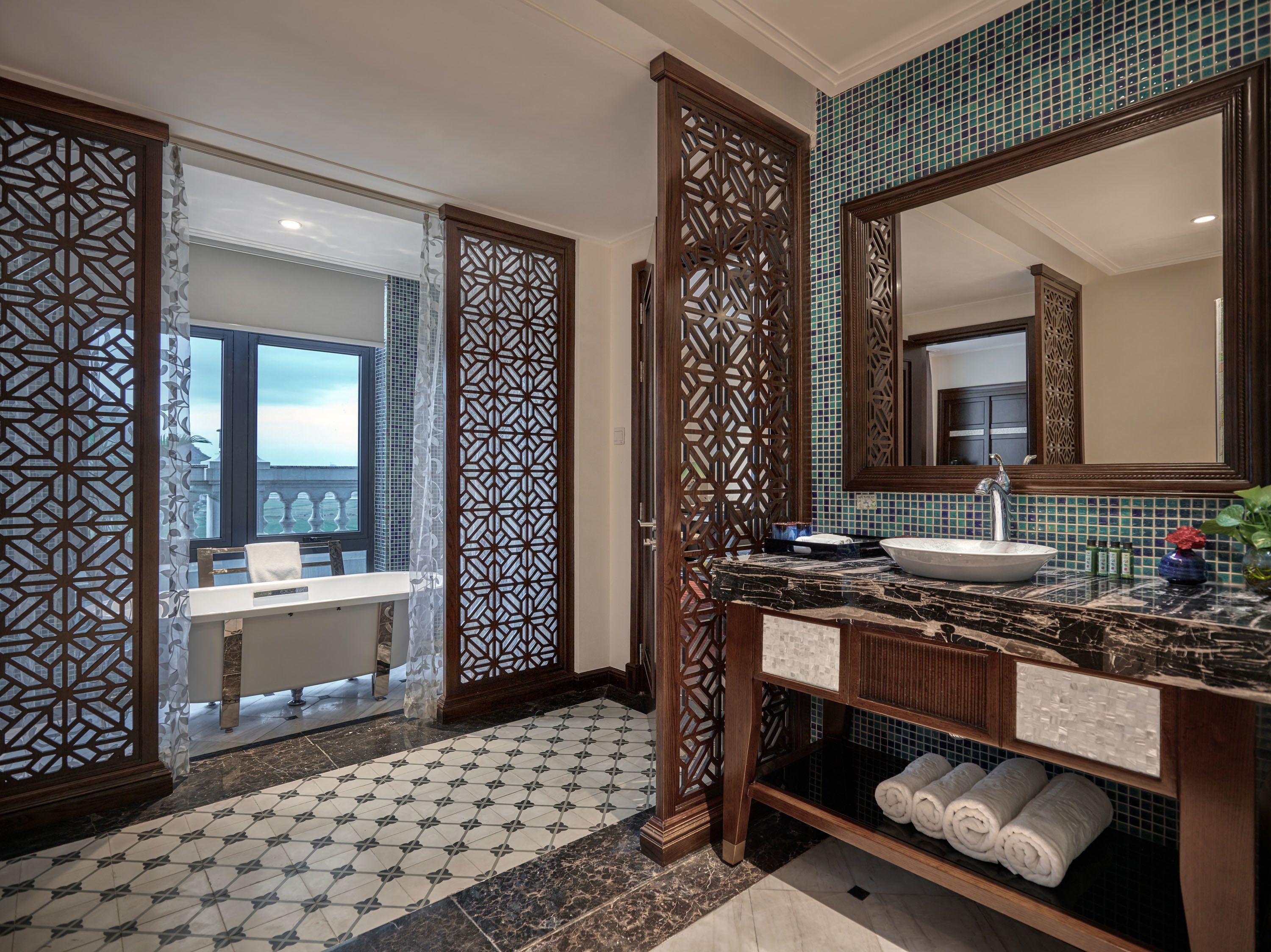 A bathroom with a large mirror, a sink with a marble countertop, and a decorative wooden partition.