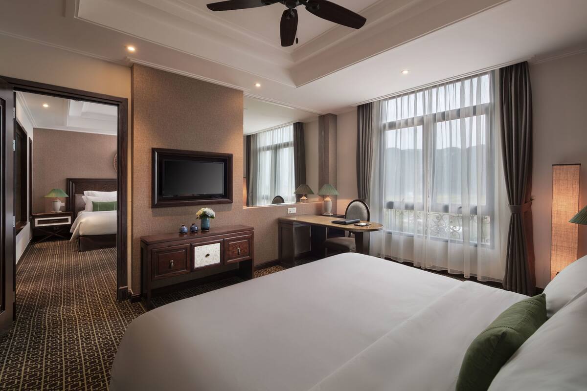 Une chambre d’hôtel avec un grand lit, un bureau, une télévision et une vue sur la ville.