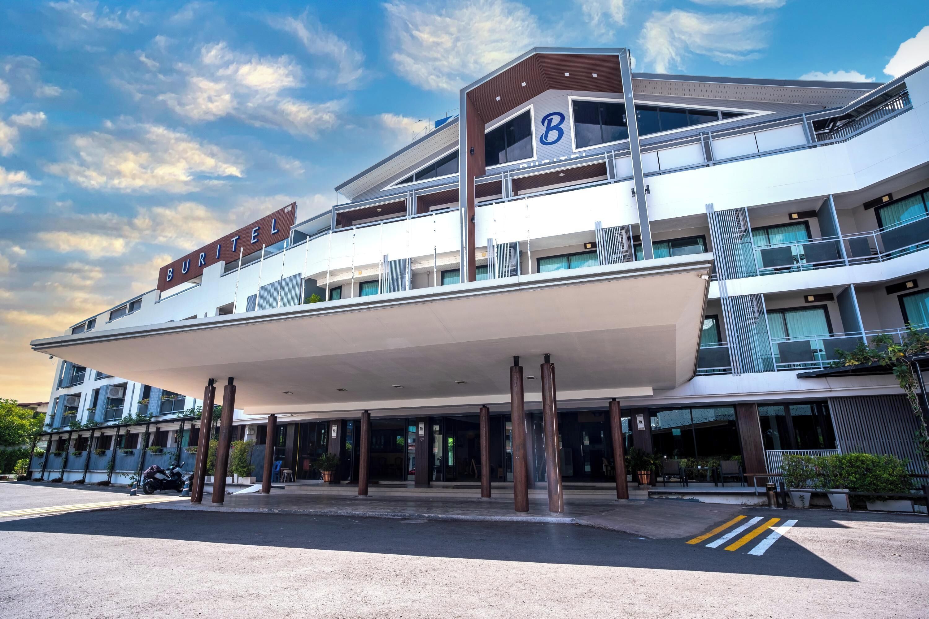 A modern hotel with a prominent 'B' sign, multiple balconies, and a covered entrance area.