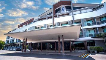A modern hotel with a prominent 'B' sign, multiple balconies, and a covered entrance area.