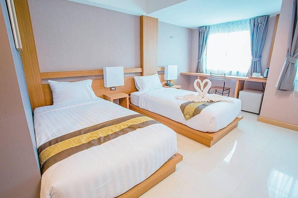 A hotel room with two beds, a desk, and a chair.