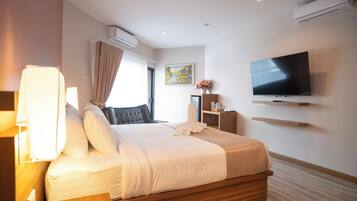 Una habitación de hotel moderna con cama, mesita de noche, televisor, aire acondicionado y un cuadro en la pared.